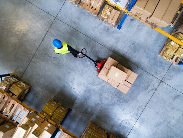 Male warehouse worker pulling a pallet truck