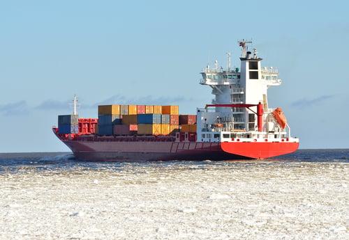 cargo container ship sailing in sea full of ice in winter
