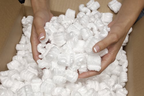 Closeup of female hands holding heap of packing peanuts in cardboard