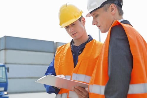 Workers discussing over clipboard