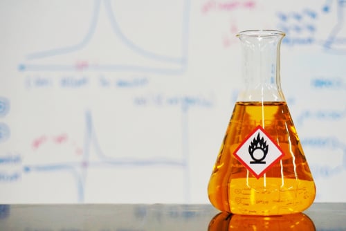 Erlenmeyer flask with Orange liquid and chemical hazard warning symbols