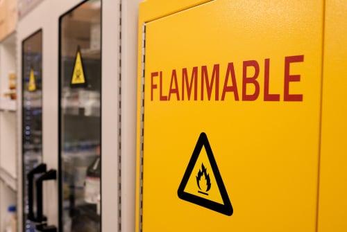 Close up black flammable sign with red letter flammable on doors of yellow flammable cabinet