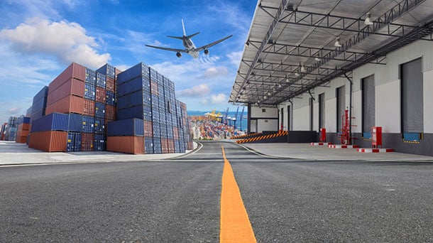 an Airplane flying over a shipping yard