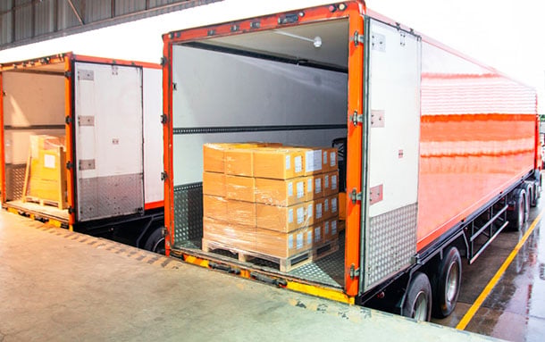 a couple of cargo freight trucks unloading at a dock